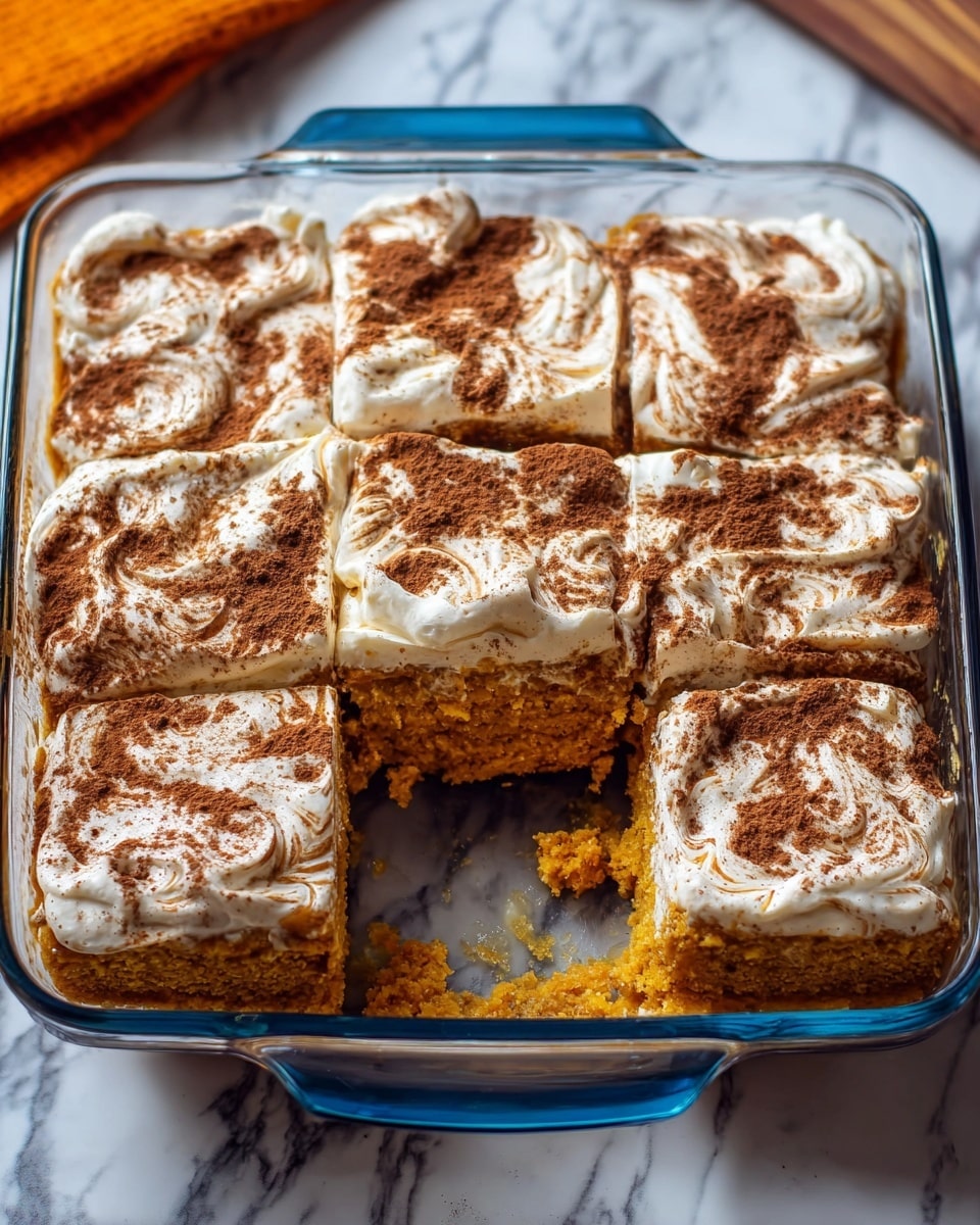 The image shows a glass baking dish with six square pieces of a layered dessert inside. The bottom layer is a thick, soft pumpkin-colored cake with a moist texture. On top, there is a thick white layer of creamy frosting that looks fluffy and smooth. The top of the dessert is sprinkled unevenly with a generous dusting of dark brown cinnamon powder. One piece is slightly pulled out, revealing the moist texture of the cake beneath. The dish is placed on a surface with a white marbled texture; in the background, some oats in a glass jar and a pumpkin are visible, adding to the autumn feel. photo taken with an iphone --ar 4:5 --v 7