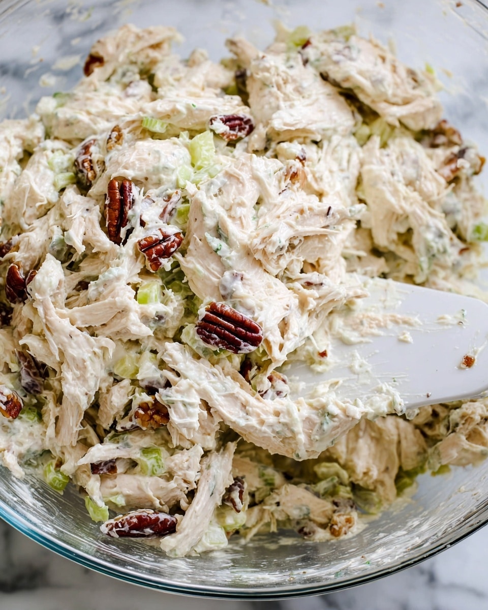 The image shows a white plate with two halves of a wrap neatly cut to reveal the inside layers. The wrap consists of a soft, light beige tortilla outside, followed by a layer of dark green and light yellow leafy lettuce, then a thick filling of creamy, shredded light tan chicken mixed with small bits of white onion and some darker pieces that appear to be bacon. Behind the wrap, there are a few crispy reddish-brown bacon strips placed on the plate. In the background, there are two white bowls, one filled with more lettuce and the other with the same creamy chicken mixture, all set against a white marbled surface and a light stone-textured wall. photo taken with an iphone --ar 4:5 --v 7