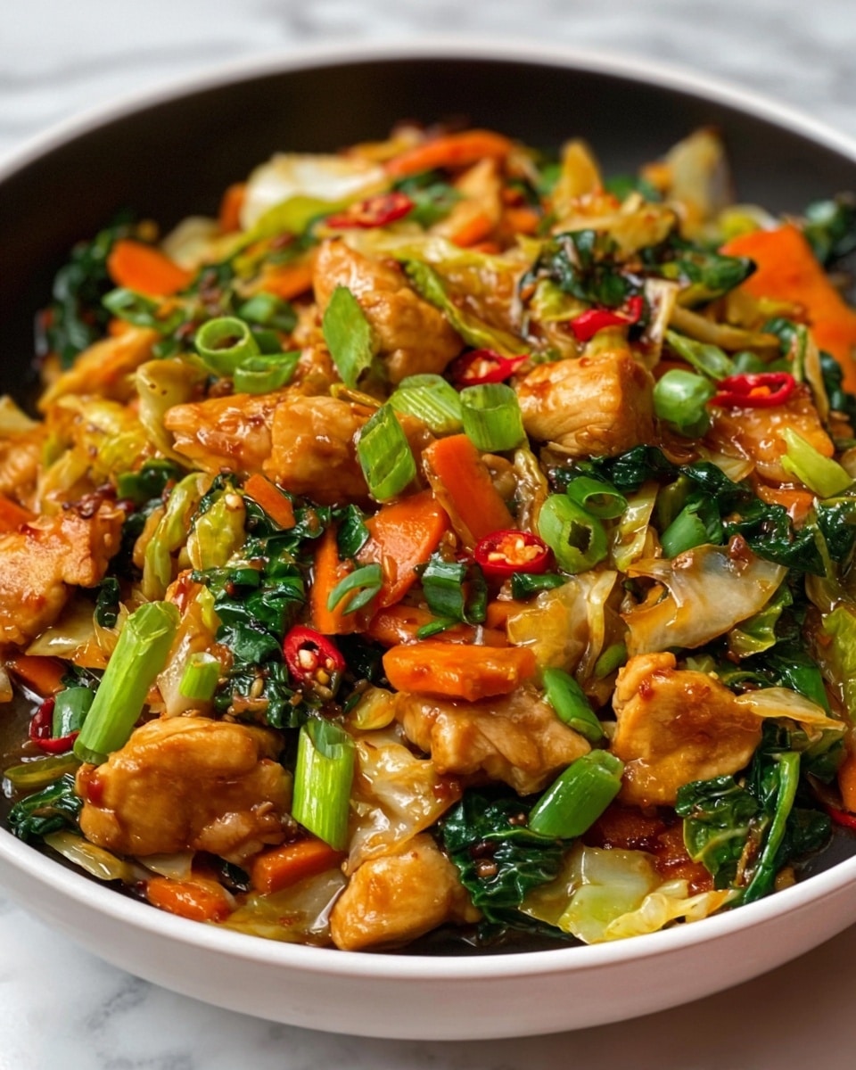 The image shows a close-up of a white bowl filled with a colorful stir-fry dish. The dish has several layers with chunks of golden brown chicken pieces mixed with orange carrot slices, bright green onions, dark green leafy vegetables, light cabbage pieces, and small red chili slices scattered throughout. The textures vary from tender chicken to crunchy vegetables, all glistening with sauce that gives a shiny appearance. The bowl sits on a white marbled surface. photo taken with an iphone --ar 4:5 --v 7