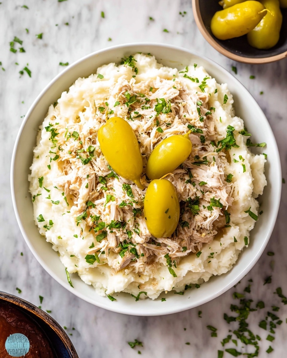 A black cooking pot filled with shredded chicken that is light brown with slightly darker browned edges, creating a fibrous texture all over. On top of the chicken are four yellow-green pepperoncini peppers placed unevenly, adding pops of shiny yellow-green color against the meat. Two metal forks are stuck into the chicken near the center, their handles pointing upward and the prongs pressing into the shredded pieces. The inside walls of the pot are dark with some food residue visible. Photo taken with an iphone --ar 4:5 --v 7