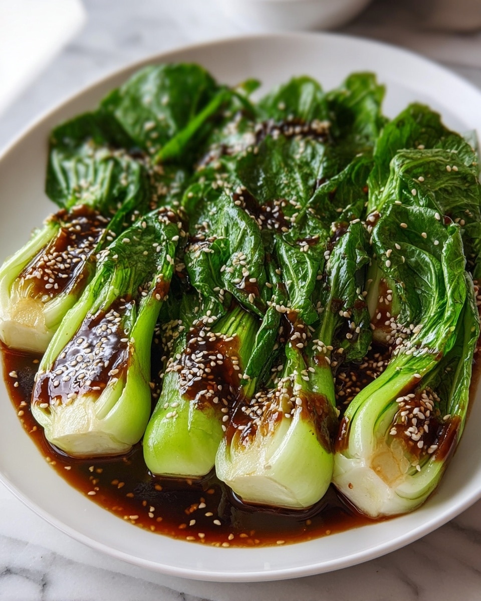 The image shows four large pieces of cooked bok choy placed side by side on a white plate. Each piece has bright green, slightly wilted leaves on top with thick, pale green to white stems at the bottom. A rich, dark brown sauce with a glossy texture is spread over the bok choy, pooling slightly at the base. The sauce is sprinkled with light-colored sesame seeds, adding a little texture and contrast. The plate sits on a white marbled surface, with a soft-focused background that suggests a cozy kitchen. photo taken with an iphone --ar 4:5 --v 7
