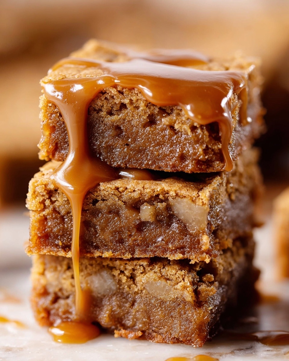 The image shows a close-up of a stack of three thick, square blondies with a chewy, dense texture and golden brown color. The top blondie is topped with a smooth pool of glossy caramel sauce slowly dripping down the side. The blondies have visible small chunks inside, adding texture, with some edges slightly crisp and cracked. The background is softly blurred, making the blondie stack the clear focus, all on a white marbled texture. Photo taken with an iphone --ar 4:5 --v 7