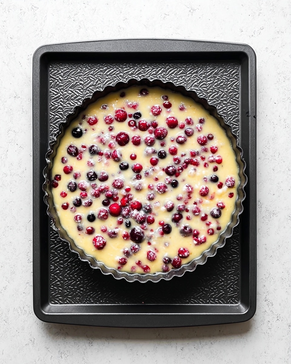A round light yellow cake with bright red berries baked inside, cut into eight triangular slices and placed on a white plate, the cake top dusted with powdered sugar giving a soft white finish, one slice being lifted by a silver cake server; the white marbled surface beneath has a subtle pattern with pale gray veins, adding a clean and fresh look to the scene. photo taken with an iphone --ar 4:5 --v 7