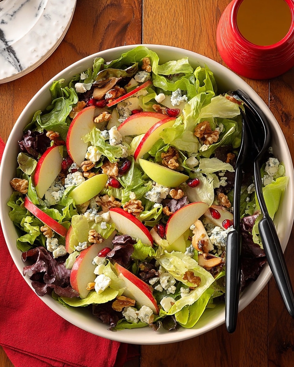 A white bowl filled with a fresh green salad showing about five layers: the bottom layer is mixed green lettuce leaves of different shades, some light green and some dark red, with a crisp texture. On top of the greens are thin slices of red apple and yellow pear, arranged evenly around the bowl. Scattered over the fruit and greens are small chunks of blue cheese and pieces of light brown walnuts. Red tomato cubes add a splash of bright red throughout the salad. Two black utensils, a fork and a spoon, rest inside the bowl. The bowl is set on a wooden table with a red cloth napkin on the left and a white plate with yellow and purple olives in the top left corner. Photo taken with an iphone --ar 4:5 --v 7