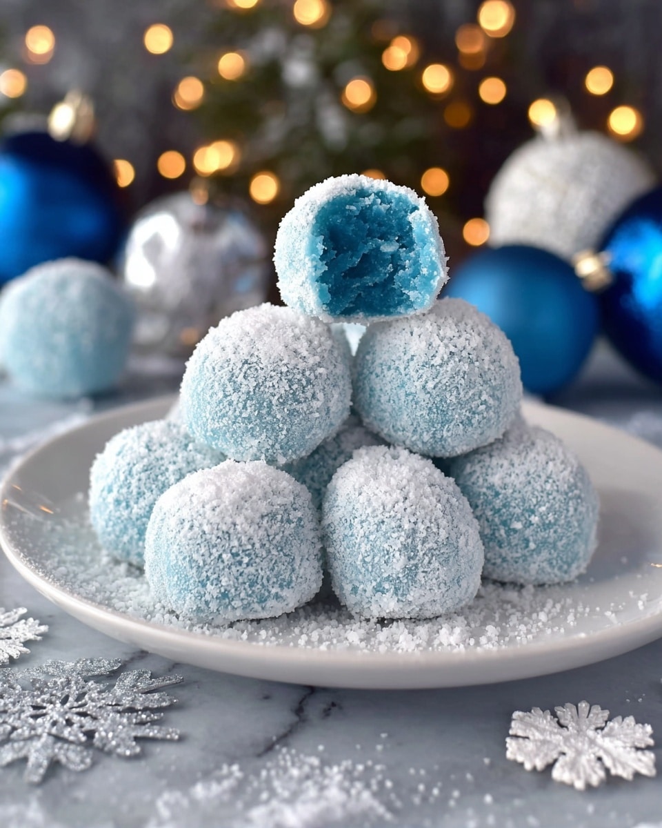 A white plate holds a pile of ten blue round balls covered evenly in shiny sugar crystals, giving them a frosty look. Two of the balls lie at the front, each with a bite taken out, revealing a smooth, dense light blue inside. The plate’s edge has small rounded bumps, and the white marbled surface underneath is sprinkled with blue and white glitter. Green pine sprigs, a silver sparkly ornament, and a white snowflake decoration are arranged softly out of focus around the plate, with warm fairy lights glowing gently in the background. photo taken with an iphone --ar 4:5 --v 7