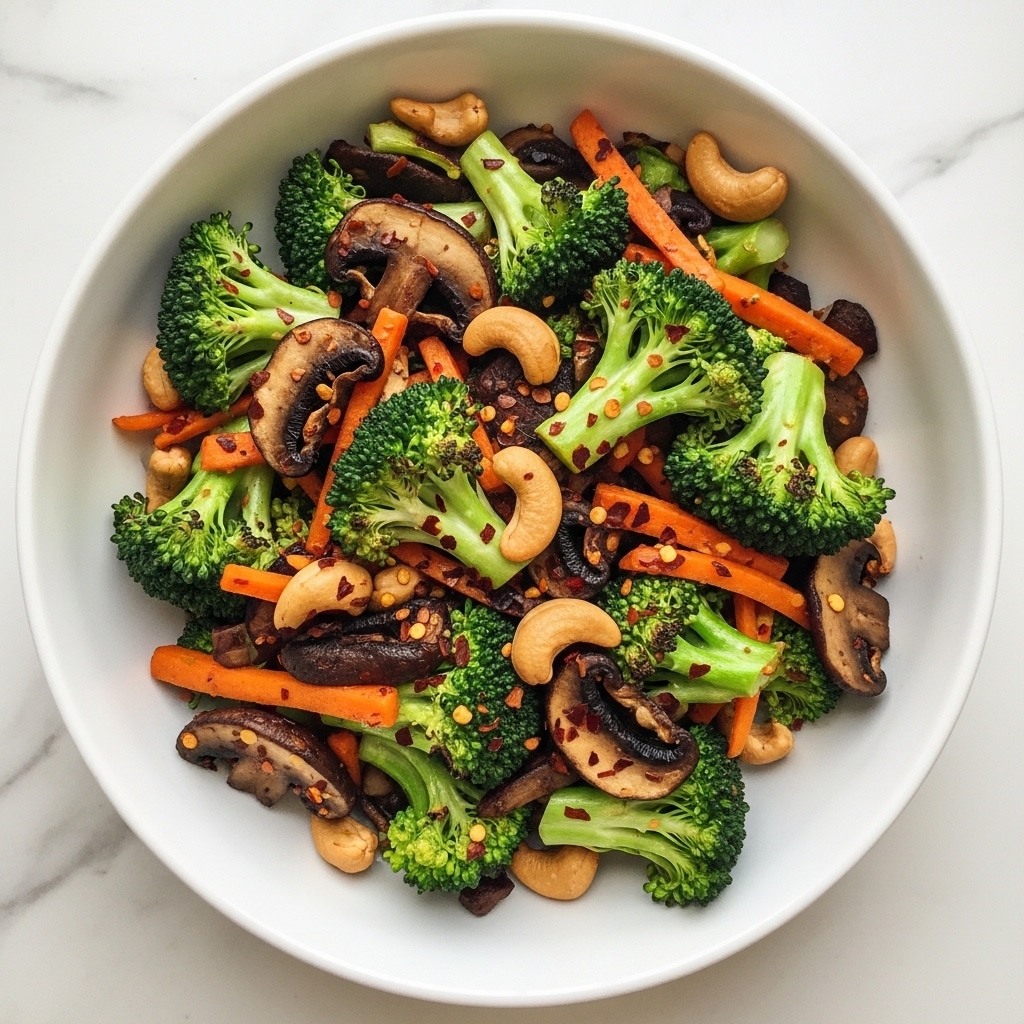 A close-up view of a dish showing several layers of sautéed vegetables and nuts on a white plate, sitting on a white marbled surface. The bottom layer has dark brown thin slices of mushrooms with a glossy texture, mixed with thin orange strips likely to be carrots. On top and throughout the dish, bright green broccoli florets with slight char marks add a rough texture. Scattered lightly among the vegetables are whole cashews, adding a smooth light tan color. Small pieces of red chili flakes and black sesame seeds sprinkled on top give extra color contrast. The dish looks freshly cooked with a shiny finish on the vegetables. Photo taken with an iphone --ar 4:5 --v 7