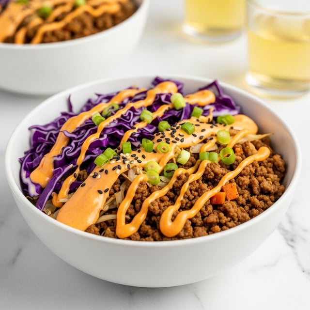 A white bowl filled with a colorful mixture consisting of three main layers: the bottom layer is ground meat cooked brown, mixed with some pale cooked shredded cabbage and orange bits of carrot; the middle layer shows vibrant purple shredded cabbage pieces scattered around; the top layer is drizzled with smooth, bright orange sauce and sprinkled with small black sesame seeds and fresh chopped green onions. The bowl sits on a white marbled surface, with blurred second white bowl of the same dish and two clear glasses filled with light yellow liquid in the background. Photo taken with an iphone --ar 4:5 --v 7
