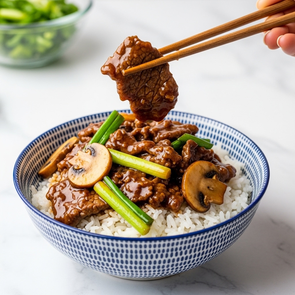 The dish is a rich stir-fry served on a white oval plate placed on a white marbled surface. It has around three layers: the base layer is glossy, dark brown strips of seitan or beef. Mixed here and on top are medium-sized curved slices of light brown mushrooms with darker edges, and long pieces of green onion showing white and green parts. The sauce covering everything is thick and shiny, creating a moist, glistening texture. In the background, to the left, there is a small clear glass bowl with chopped green onions visible. Photo taken with an iphone --ar 4:5 --v 7