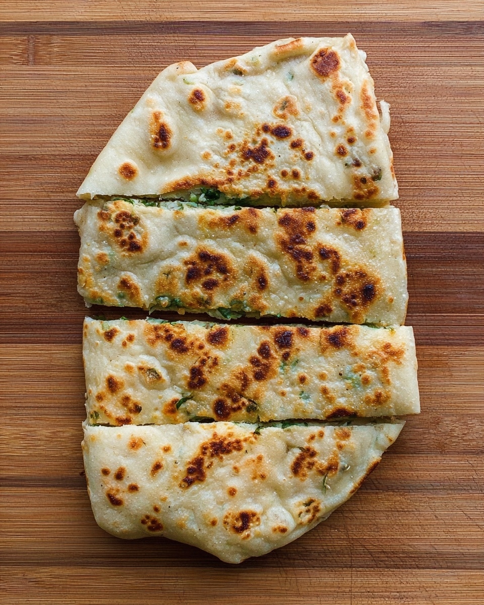 This image shows a flatbread, folded and cooked until golden brown with dark brown spots, cut into four rectangular pieces. The flatbread has a lightly blistered, soft texture with slightly bubbly and uneven browning. It sits on a wooden cutting board that has a natural striped wood grain. The flatbread looks thin and flexible, with some green filling peeking out slightly at the edges. photo taken with an iphone --ar 4:5 --v 7