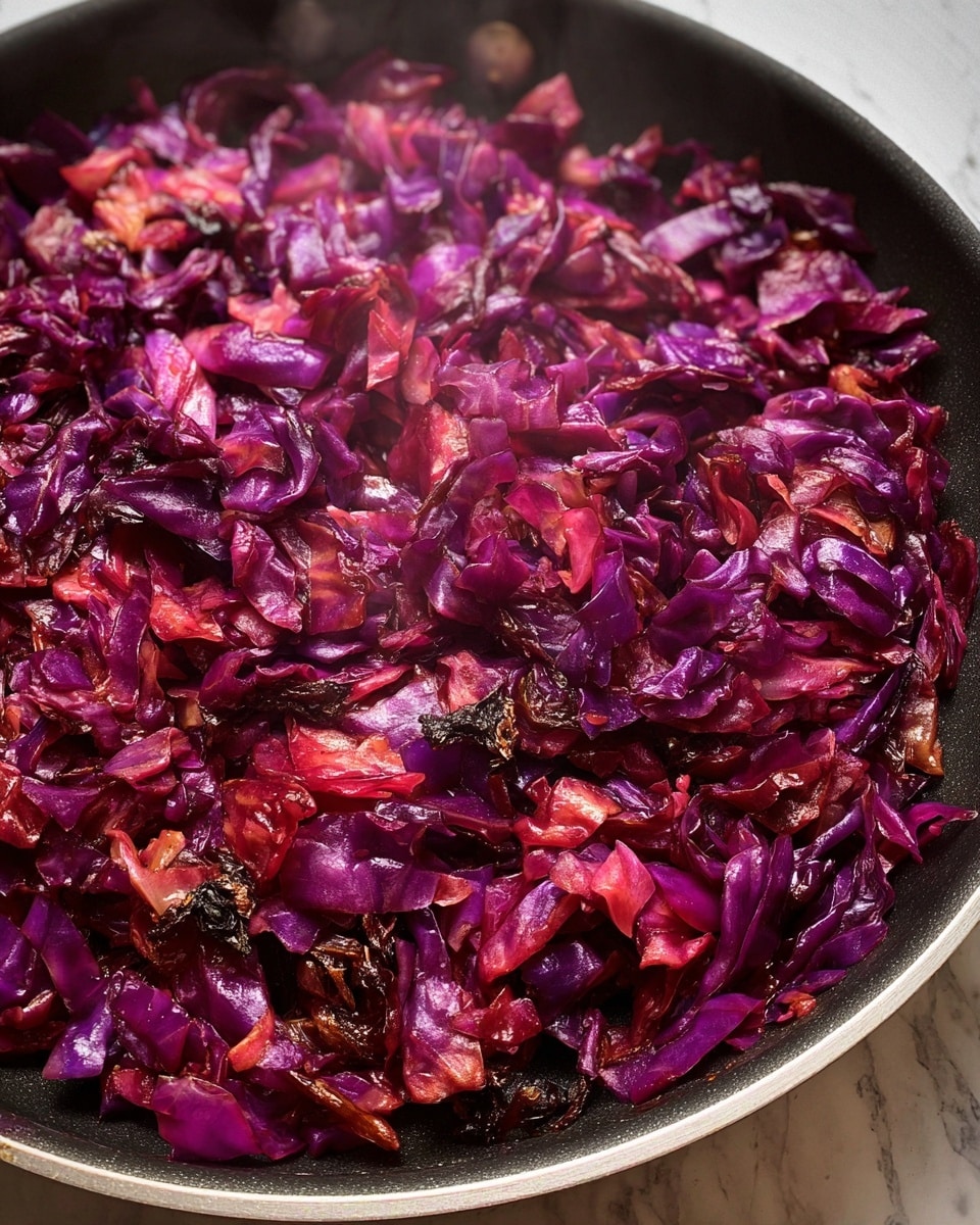 The image shows a close-up of cooked chopped red cabbage in a black pan. The cabbage pieces are glossy with a mix of deep purple and bright pink colors, with some charred, dark brown edges giving a slightly crispy look. The texture appears soft but slightly firm with some cooked juices visible. The pan is centered in the frame, and there is a faint steam rising from the cabbage, indicating it is hot. The background is a white marbled texture. photo taken with an iphone --ar 4:5 --v 7