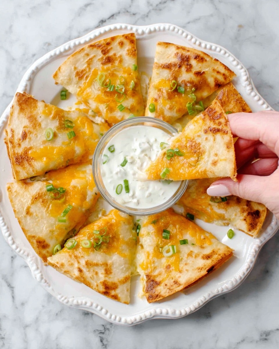 The image shows a white plate with a scalloped edge, filled with eight golden-brown quesadilla slices arranged in a circle around a small bowl of creamy white dip with green herbs inside. The quesadillas have melted yellow and orange cheese on top and small green onion pieces sprinkled over them. A woman's hand is picking up one quesadilla slice from the plate. The surface beneath the plate is a white marbled texture. photo taken with an iphone --ar 4:5 --v 7