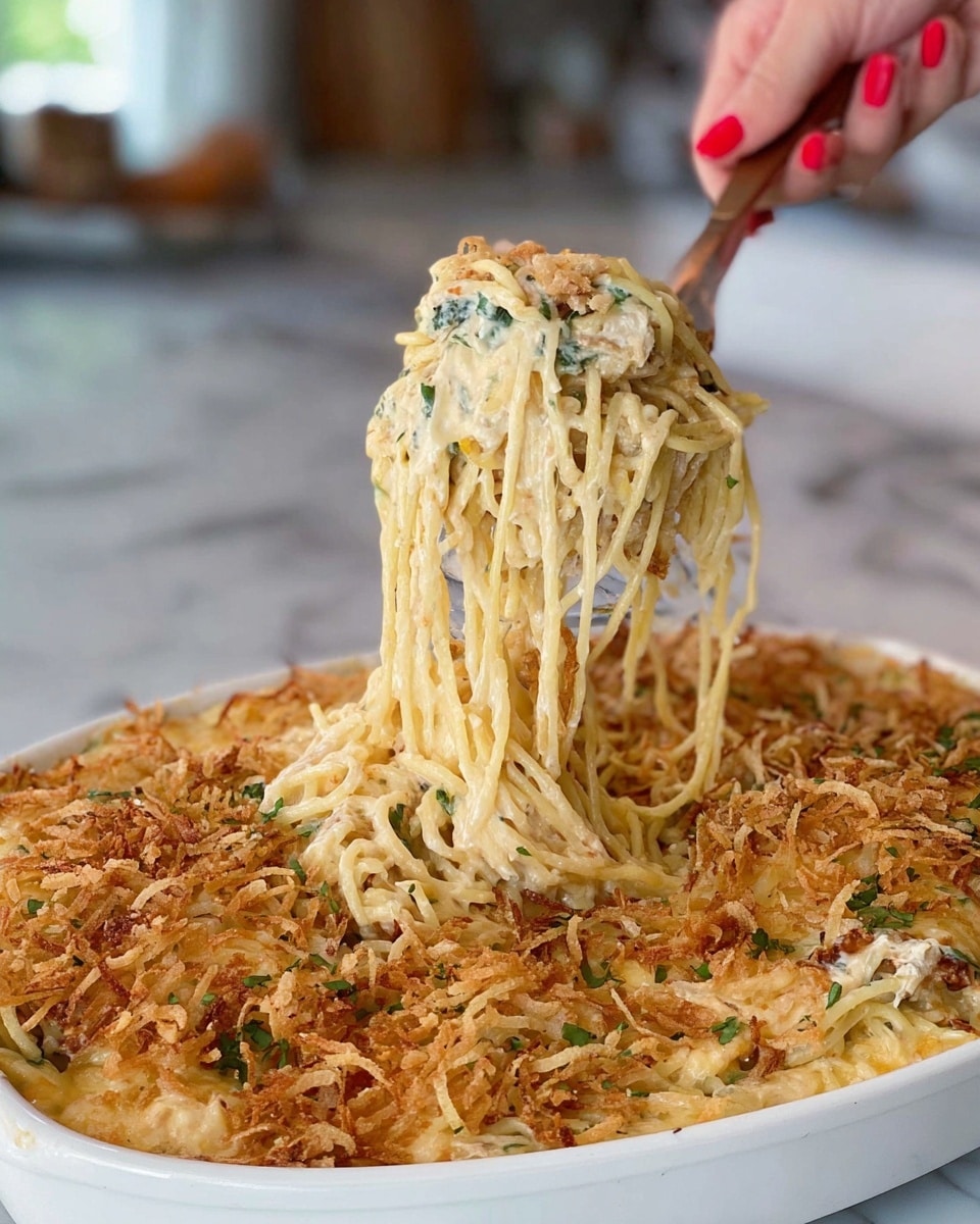 The dish is a creamy casserole in a rectangular white baking dish with a red handle, placed on a white marbled surface. It has at least three visible layers: the bottom layer is a creamy, white sauce with hints of green vegetables mixed in, the middle layer shows a mix of shredded yellow and white cheese, and the top layer is a crunchy, golden-brown topping that looks like fried onions spread evenly over the surface. The textures range from creamy and smooth at the base to crispy and crumbly on top. photo taken with an iphone --ar 4:5 --v 7