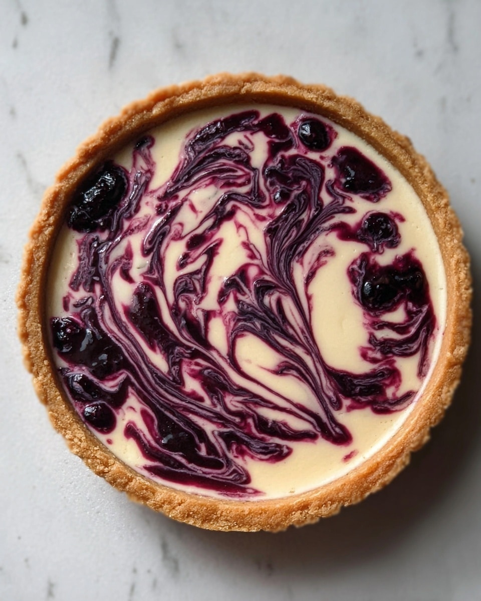 The image shows a round tart with a golden-baked crust. Inside the crust, there is a creamy white filling forming the base layer. On top of the filling, there is a swirled pattern of dark purple and violet, created by a fruit sauce or jam, possibly made of berries. The swirls create an artistic and marbled effect across the surface. The tart is placed on a flat surface with a white marbled texture. The photo is taken with an iphone --ar 4:5 --v 7