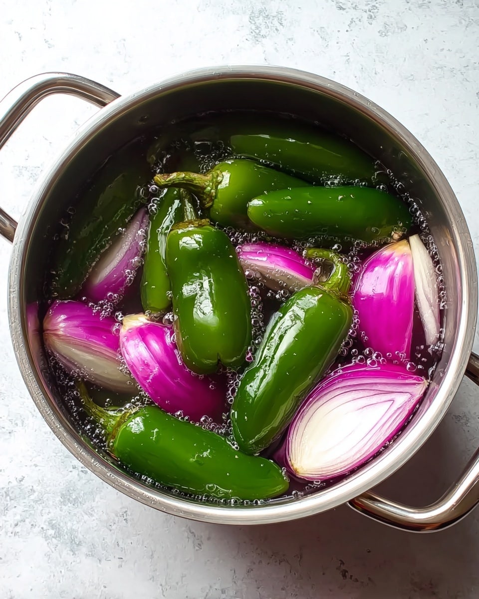 A top view of a stainless steel pot filled with water containing six whole green jalapeño peppers and several large pieces of thickly sliced red onions. The jalapeños are shiny and smooth, floating among the onion pieces, which show white and purple layers with a crisp texture. The pot handles are visible, and the pot sits on a white marbled texture surface. Small bubbles cling to the peppers and onions underwater, adding a fresh, wet look. photo taken with an iphone --ar 4:5 --v 7