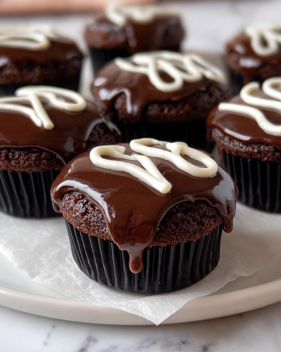 The image shows six small chocolate cupcakes arranged on a white plate lined with parchment paper, placed on a white marbled surface. Each cupcake has one main layer of dark chocolate cake with a rich, smooth layer of shiny dark chocolate ganache covering the top, slightly dripping down the sides. On top of each ganache layer, there is a decoration made from white icing, swirled in a loose, looping pattern. The cupcakes have black ridged liners, and the focus is on the foreground cupcake with others gradually blurred in the background. Photo taken with an iphone --ar 4:5 --v 7