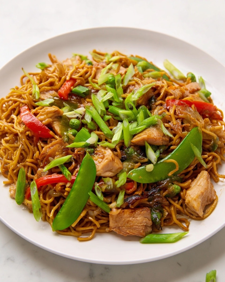 A white plate holds a serving of stir-fried noodles as the base layer, showing glossy, slightly curled brown noodles. Mixed within are small pieces of cooked chicken with a light golden-brown sear. There are few bright red sliced vegetables, such as bell peppers, and large green snow pea pods scattered on top. Fresh chopped green onions are sprinkled generously over the entire dish and a few pieces fall off onto the white marbled texture surface around the plate. The dish looks colorful with shiny textures and fresh green toppings. Photo taken with an iphone --ar 4:5 --v 7
