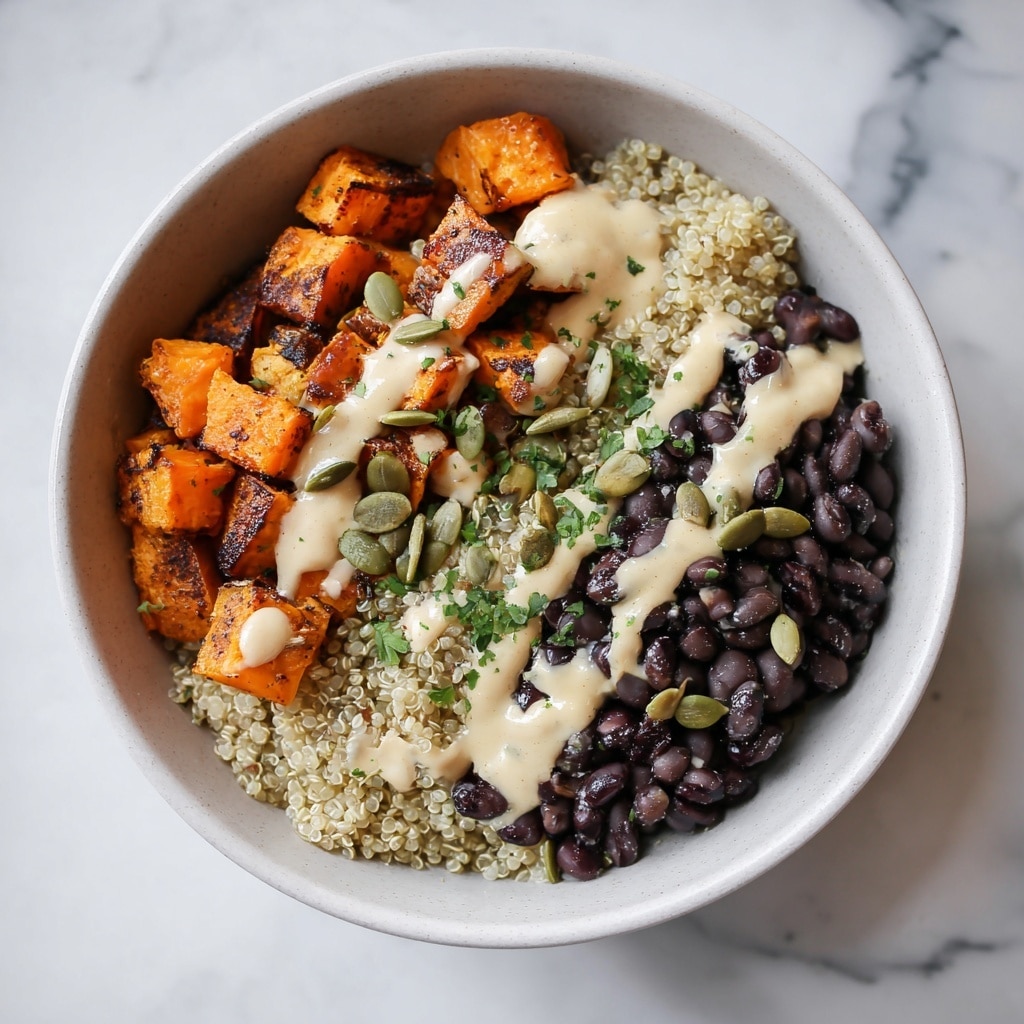 A round, white bowl with a speckled texture contains a layered dish. One layer is cooked quinoa, light beige with darker specks, spread along one side of the bowl. Next to it is a pale green mashed avocado layer. Most of the bowl is filled with roasted sweet potato cubes, bright orange-brown with some crispy edges. Scattered black beans and some green pumpkin seeds are on top of the sweet potatoes. A light creamy dressing is drizzled over everything, with small bits of fresh green herbs sprinkled across. The bowl sits on a white marbled surface with a beige cloth under it. Photo taken with an iphone --ar 4:5 --v 7