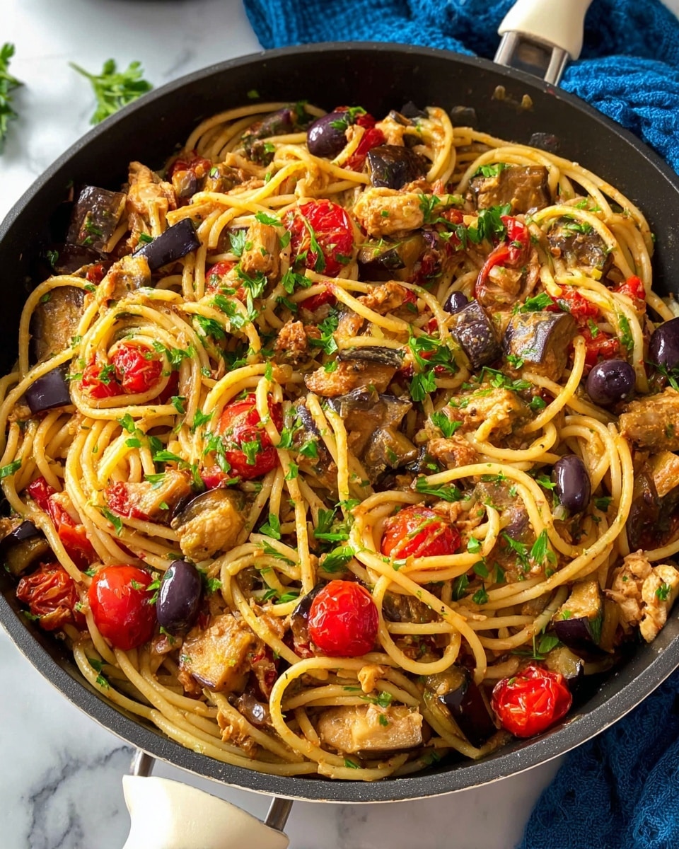 A close-up view of a black pan filled with a colorful pasta dish, showing thick spaghetti noodles that are slightly twisted and mixed with chunks of browned eggplant, bright red cherry tomatoes, small brown olives, and pieces of cooked chicken. The top is sprinkled with fresh green parsley leaves. The pan has a white handle and sits on a white marbled surface with a blue cloth partially visible. Photo taken with an iphone --ar 4:5 --v 7