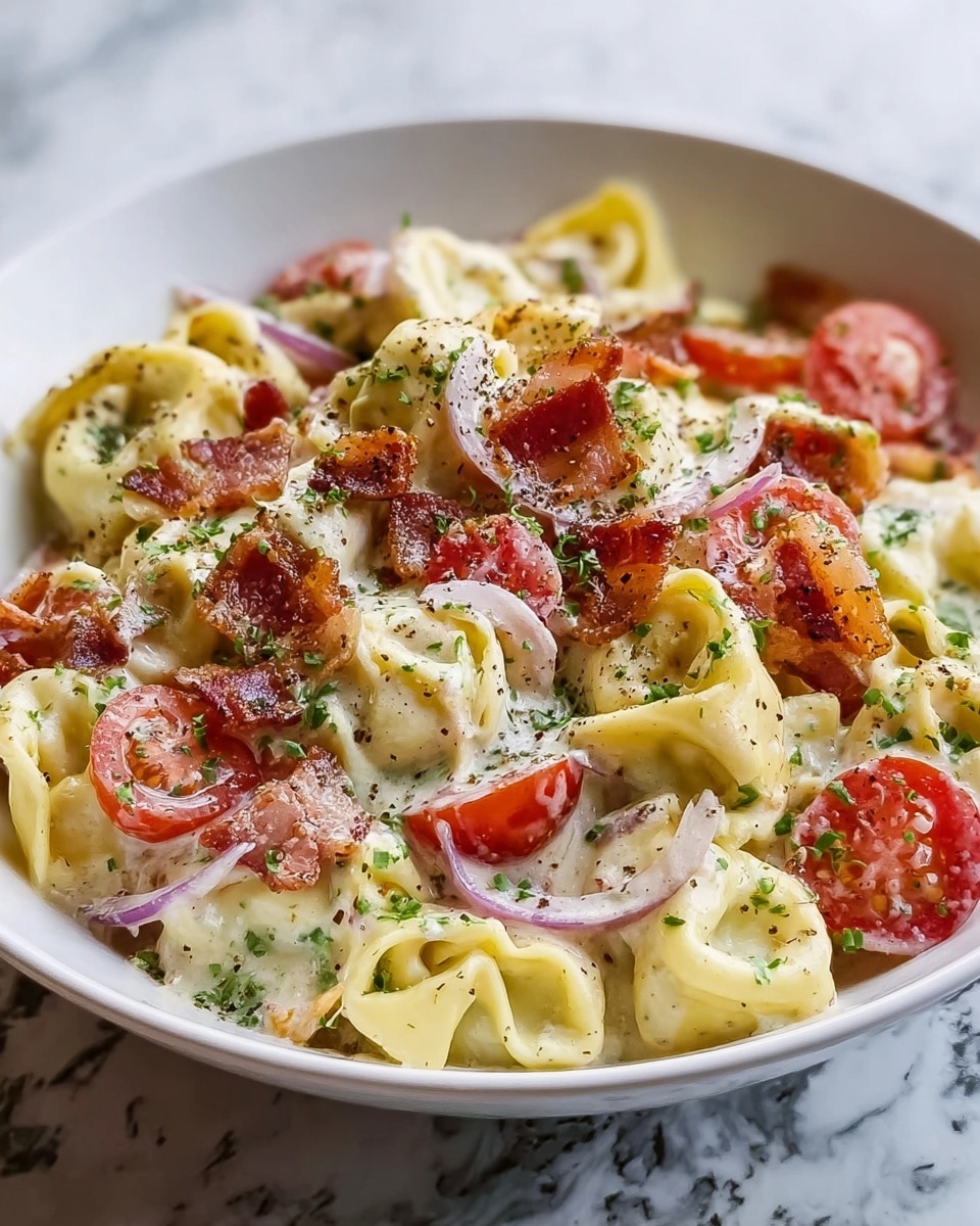 A close-up view of creamy tortellini pasta served in a white bowl placed on a white marbled surface, with about two layers visible. The bottom layer has green leafy herbs and bits of thinly sliced red onion adding pops of color. On top, the tortellini pieces are coated in a rich white sauce with a smooth, creamy texture. Small pieces of crispy bacon, red and brown in color, are scattered evenly over the pasta. Sprinkled finely grated parmesan cheese and ground black pepper are dotted on the top. A fork holds up one tortellini piece, showing off the creamy filling inside and crispy bacon on the side. Photo taken with an iphone --ar 4:5 --v 7