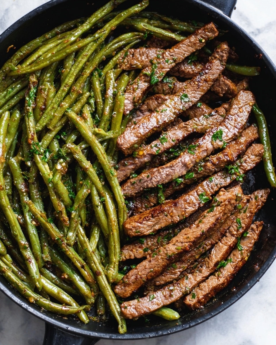 The image shows a black pan filled with cooked green beans and thin strips of grilled steak. The green beans form a layer on one side of the pan, looking shiny and slightly wrinkled with a green color mixed with bits of seasoning. The steak strips cover the other side, brown and seared with a light crust and some visible grill marks, sprinkled with fresh chopped herbs. The food looks arranged neatly in two sections inside the pan, placed on a white marbled surface. Photo taken with an iphone --ar 4:5 --v 7