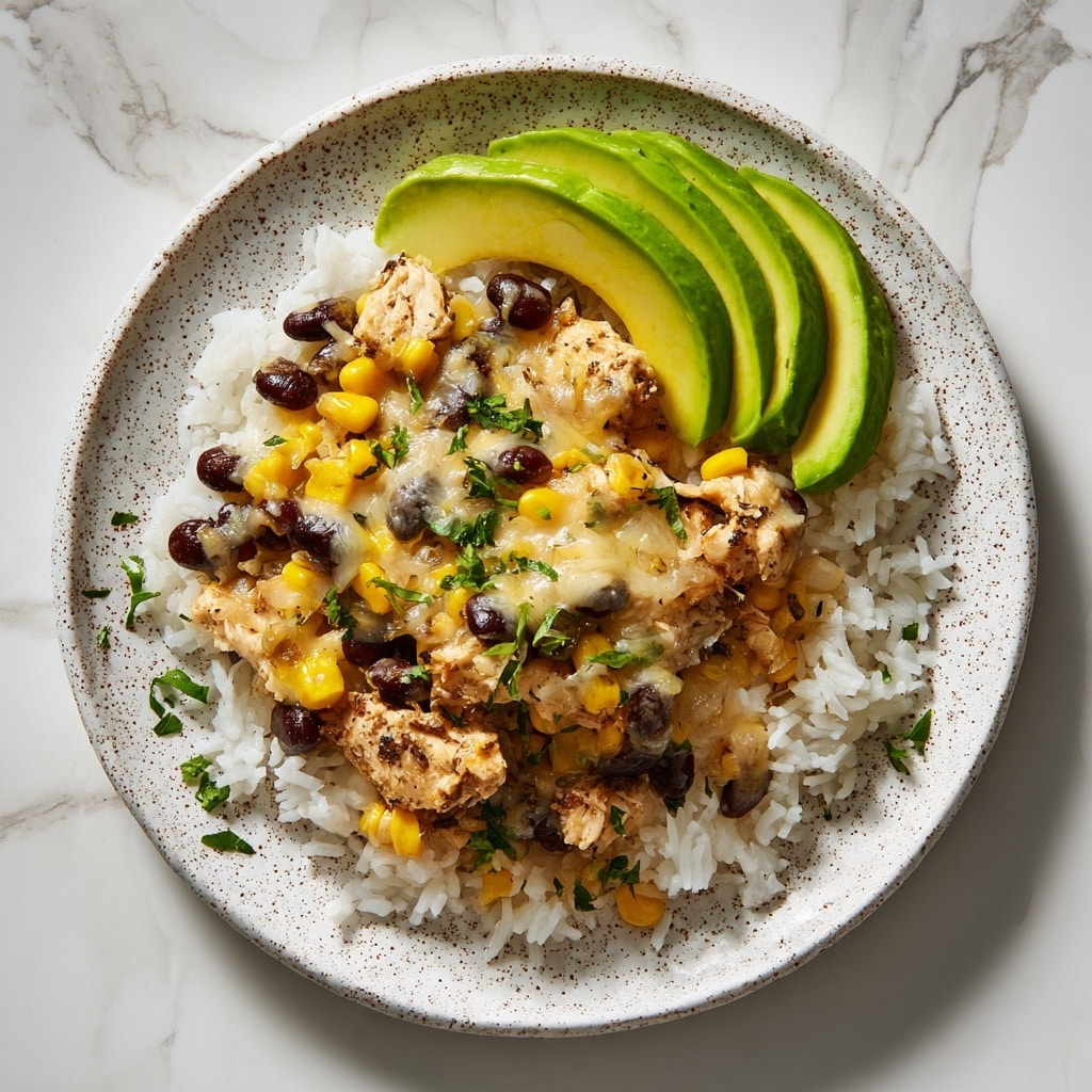A white speckled plate holds a layered dish starting with a base of white rice. On top of the rice, there are pieces of cooked chicken mixed with black beans and yellow corn kernels. Melted cheese is scattered over the chicken, beans, and corn, adding a creamy, slightly browned texture. Three slices of bright green avocado rest on one side of the plate, adding fresh color. Small green herb pieces are sprinkled on top for garnish. The plate is set on a white marbled surface. photo taken with an iphone --ar 4:5 --v 7